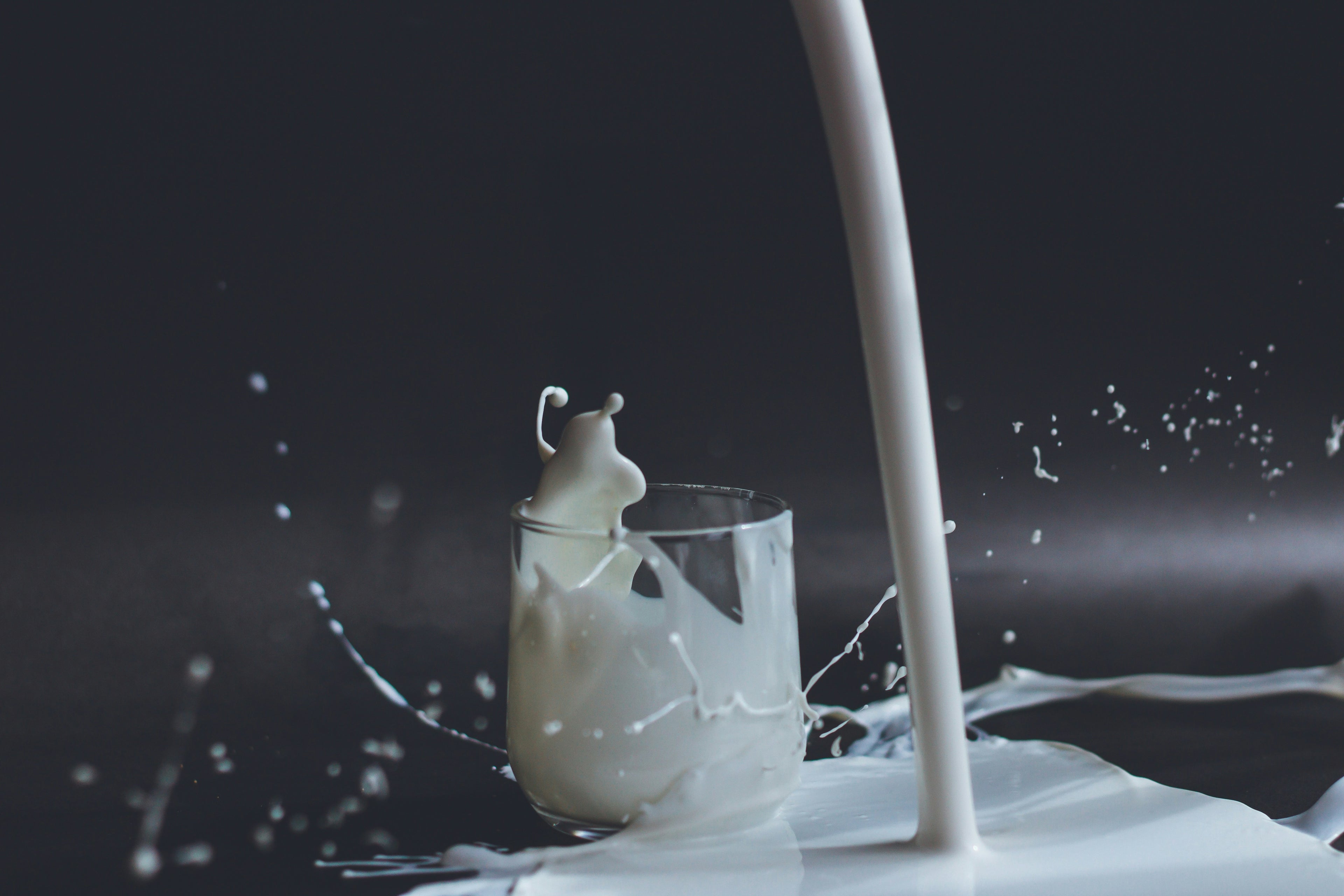 Milk being poured into a glass with a dark background